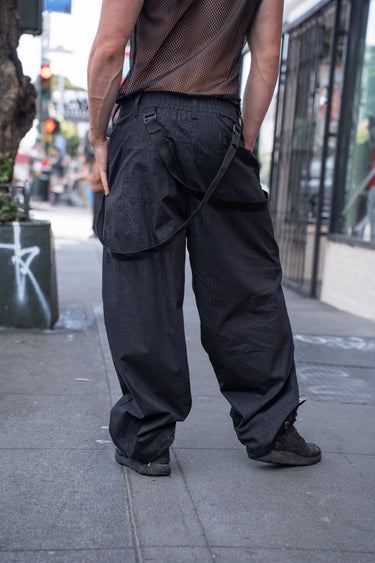 Unisex Combat runic Pants in black with tonal Runic print and buckle straps, back view
