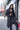 Black Runic Cardigan worn with the hood up, showing the tonal print and draped open front.