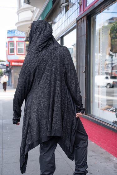Back view of the black Runic Cardigan showing the hood, tonal print, and asymmetric hem.
